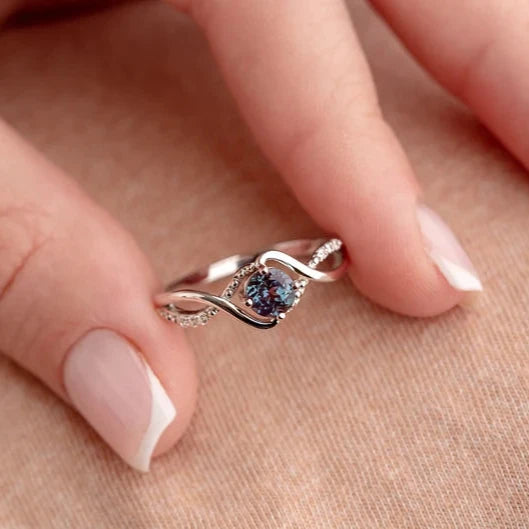 Detail shot of the June Birthstone Elegance ring held by model's fingers, showcasing the Alexandrite and gold-plated silver band