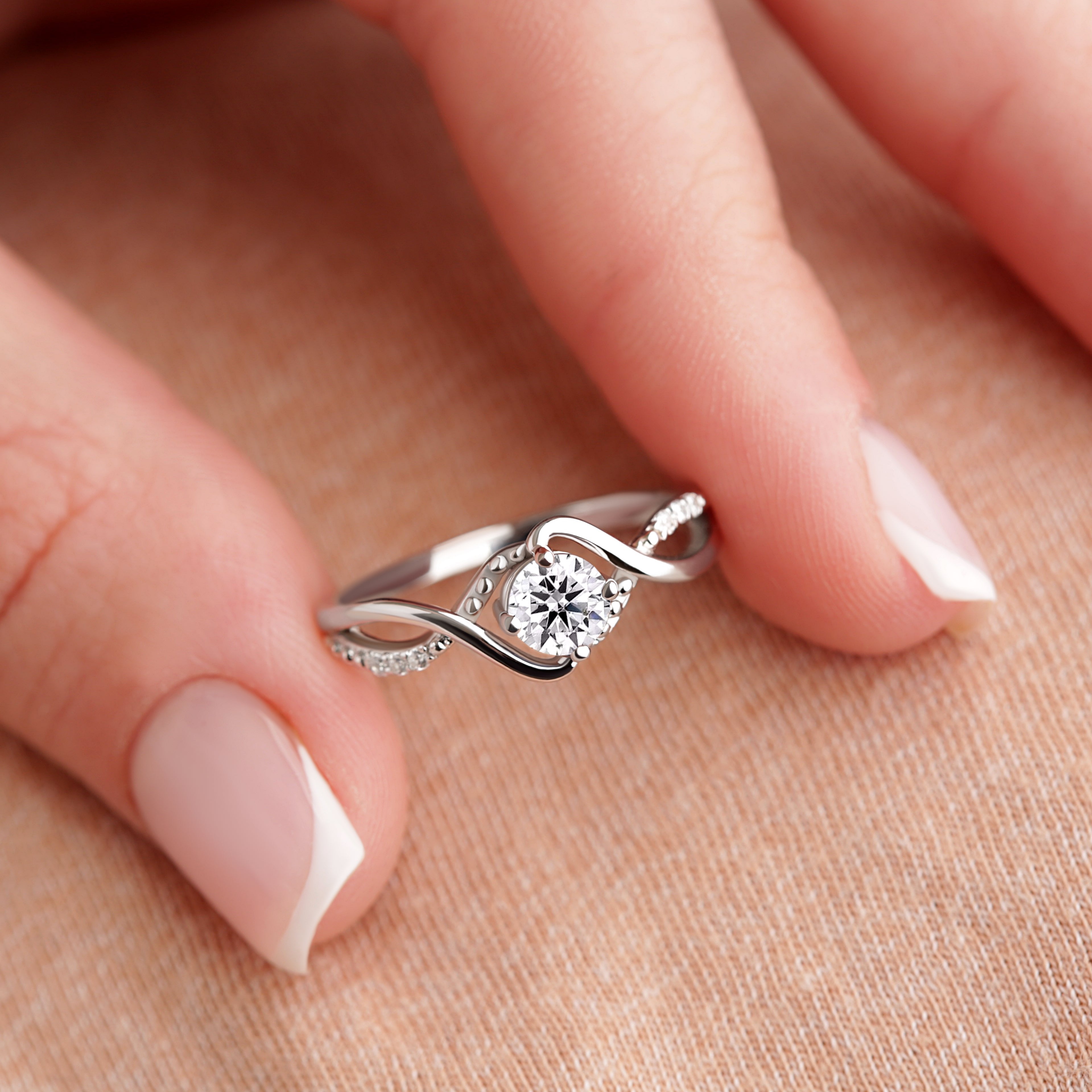 Close-up of the Bridal Elegance in Silver and Gold ring held at the fingertips, featuring a moissanite gemstone with a gold-plated silver band.