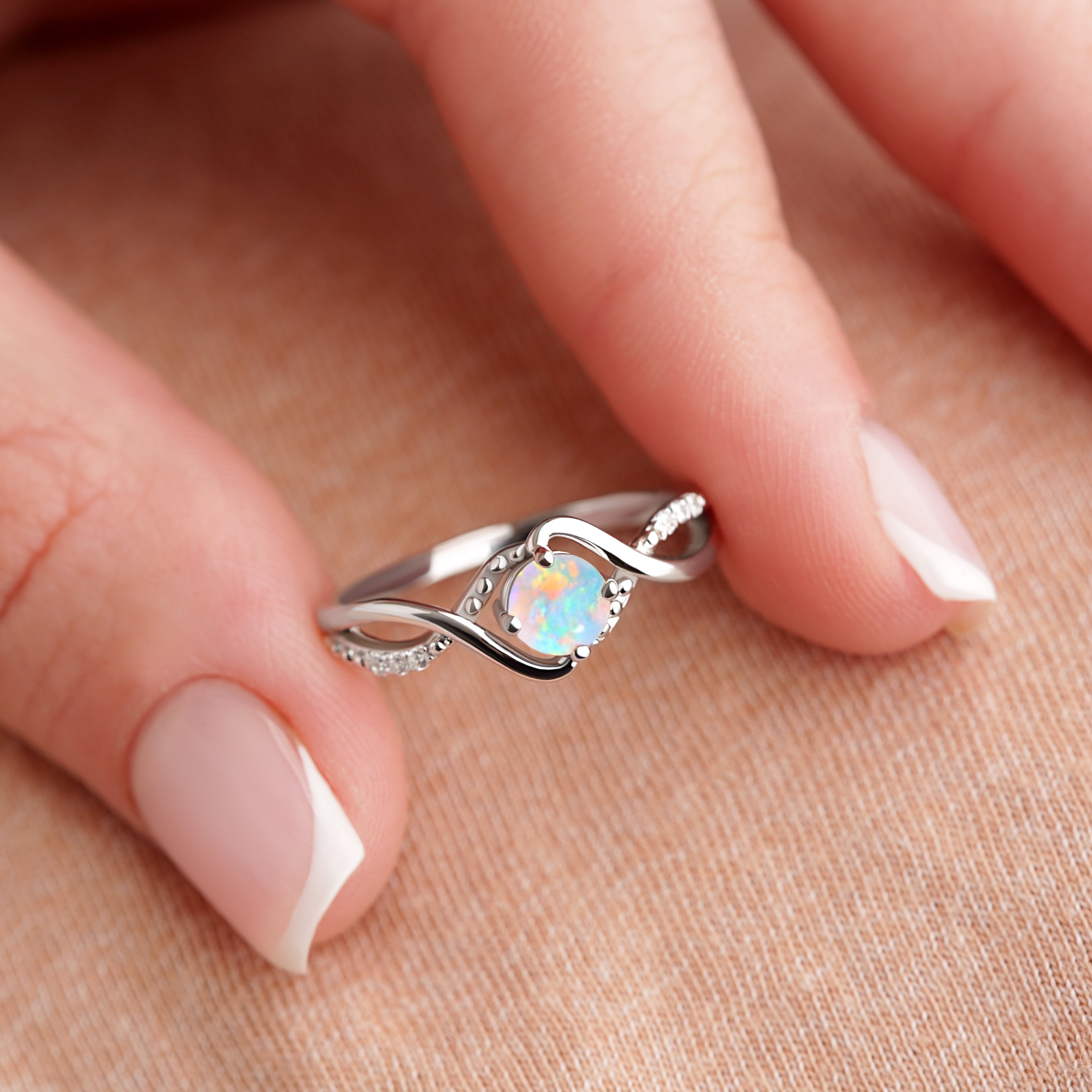 Close-up of the Bridal Opal Art Deco Treasure ring in fingertips, showcasing the 5mm White Opal and gold-plated sterling silver band.