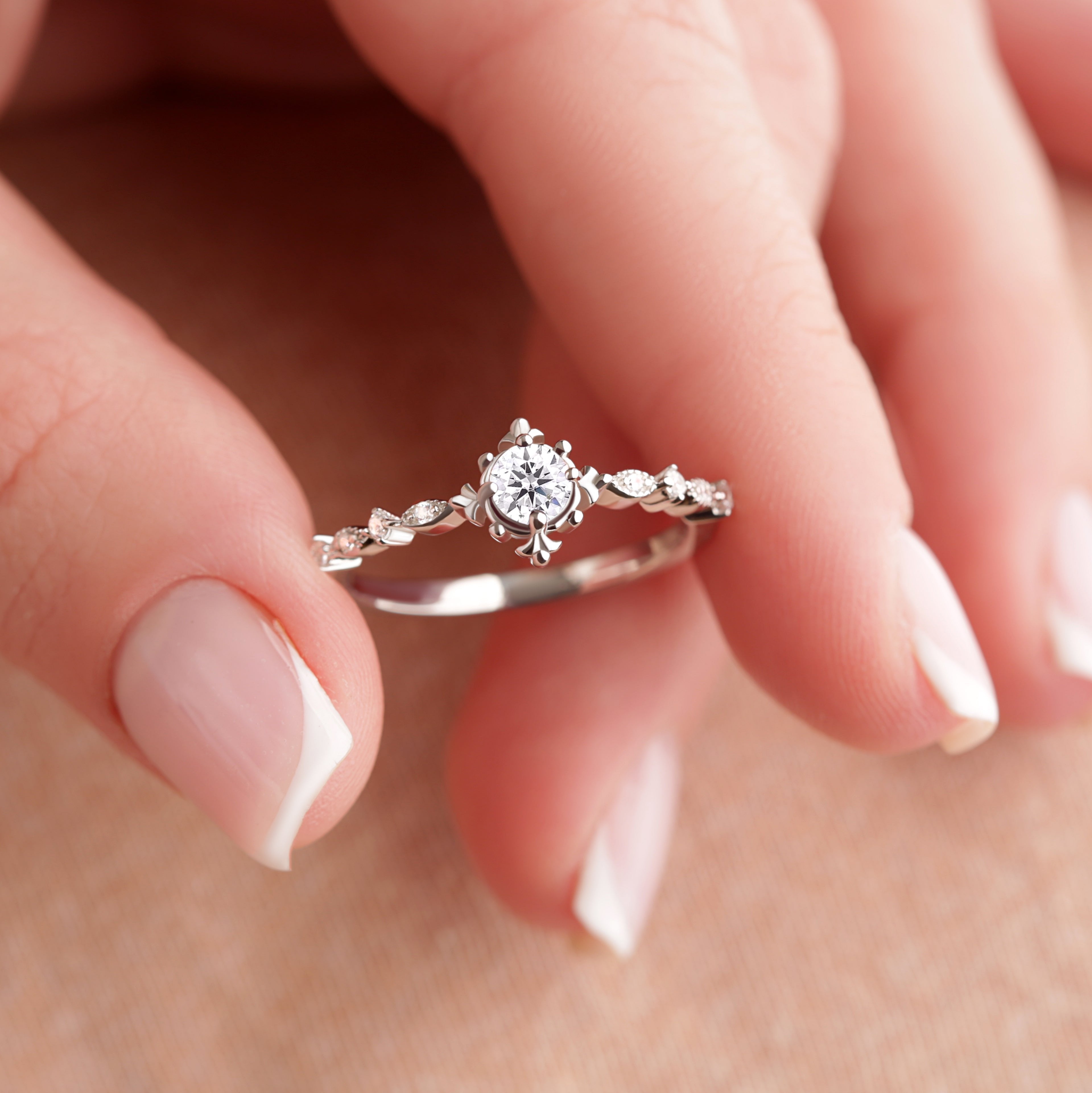 The Brisbane Unique Vintage Moissanite Engagement Ring in silver gold, held delicately by fingertips, emphasizing its vintage charm and exquisite craftsmanship.