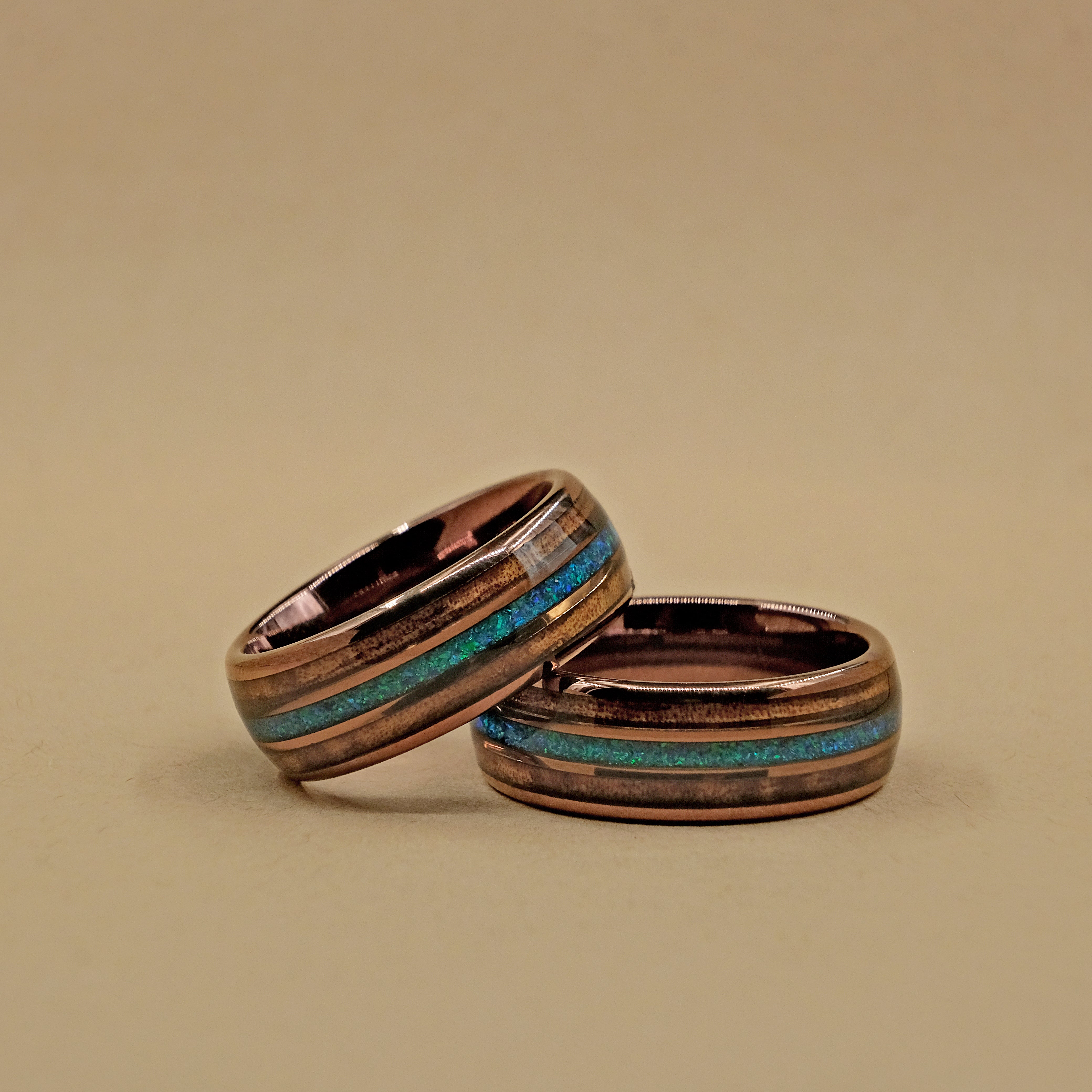 Hawaiian Koa Wood Wedding Ring set placed horizontally, highlighting the natural beauty of the Koa wood and the brilliance of the opal inlay.