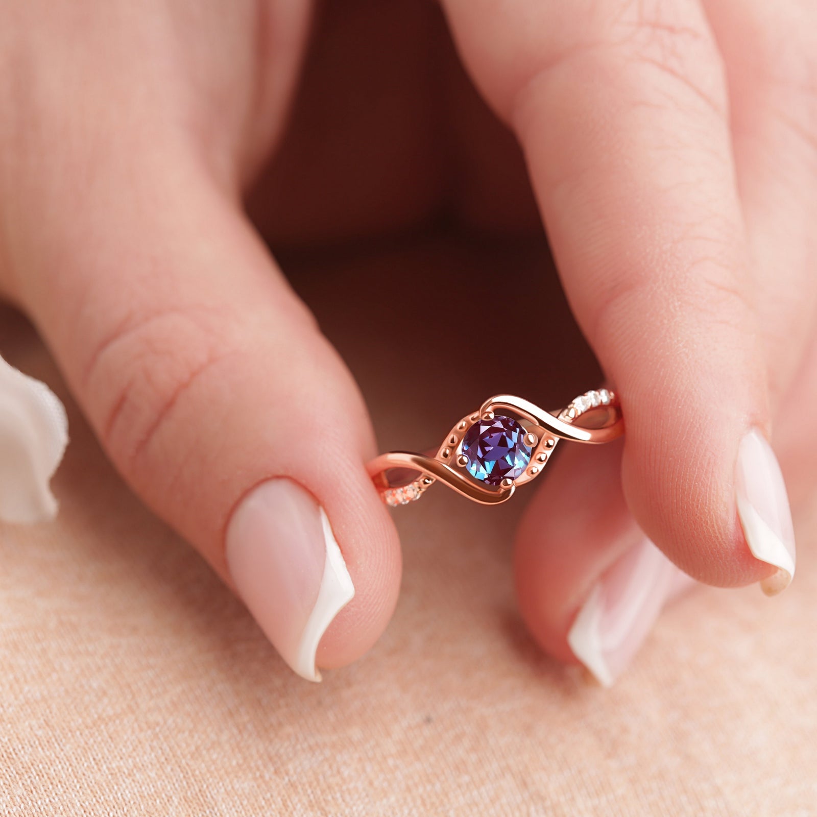 Rose Gold Vermeil Alexandrite Engagement Ring displayed on a model's fingertips, highlighting the elegant design and color-changing Alexandrite gemstone.