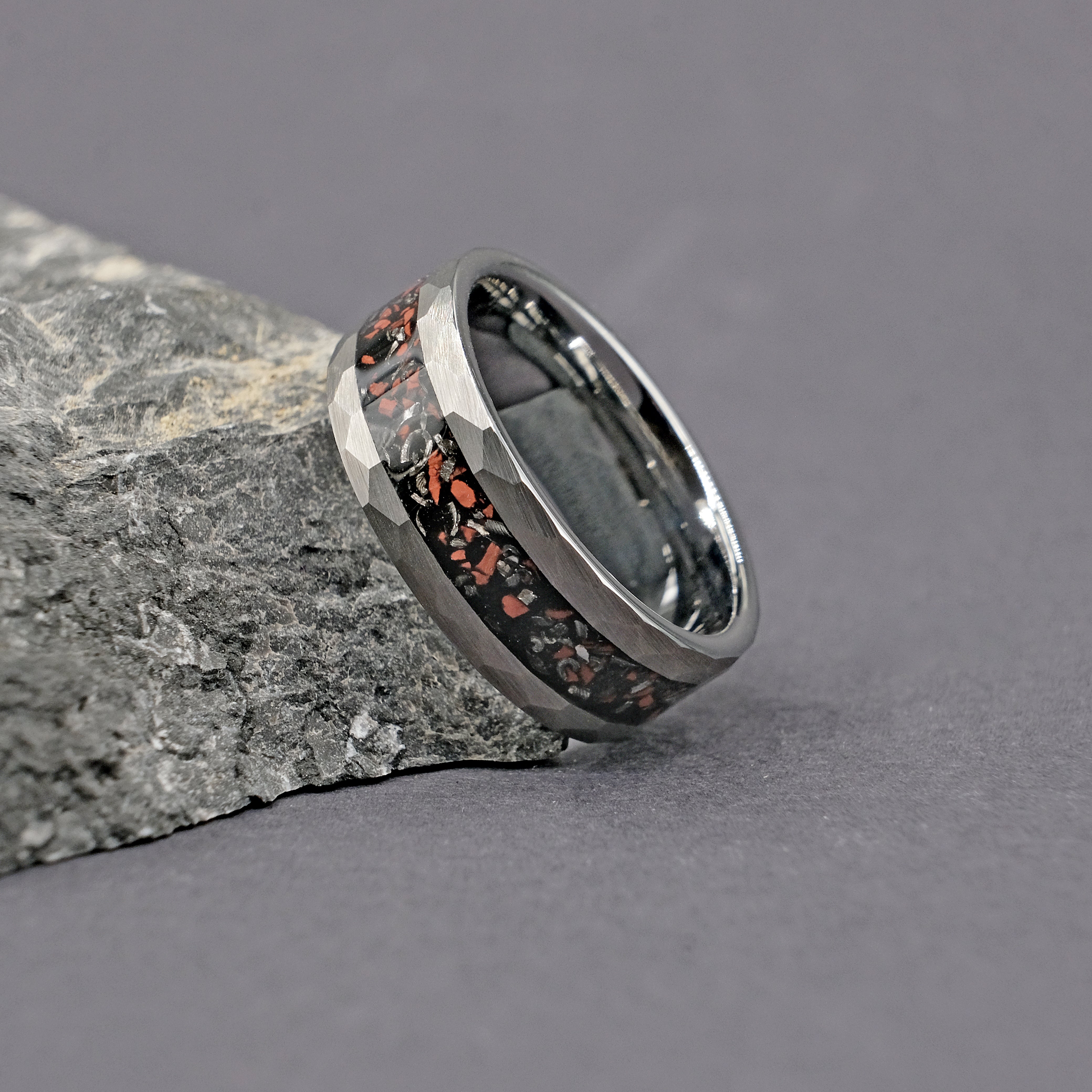 Silver Dinosaur Bone Wedding Ring standing vertically next to a rock, emphasizing the ancient and rugged materials used in its design.