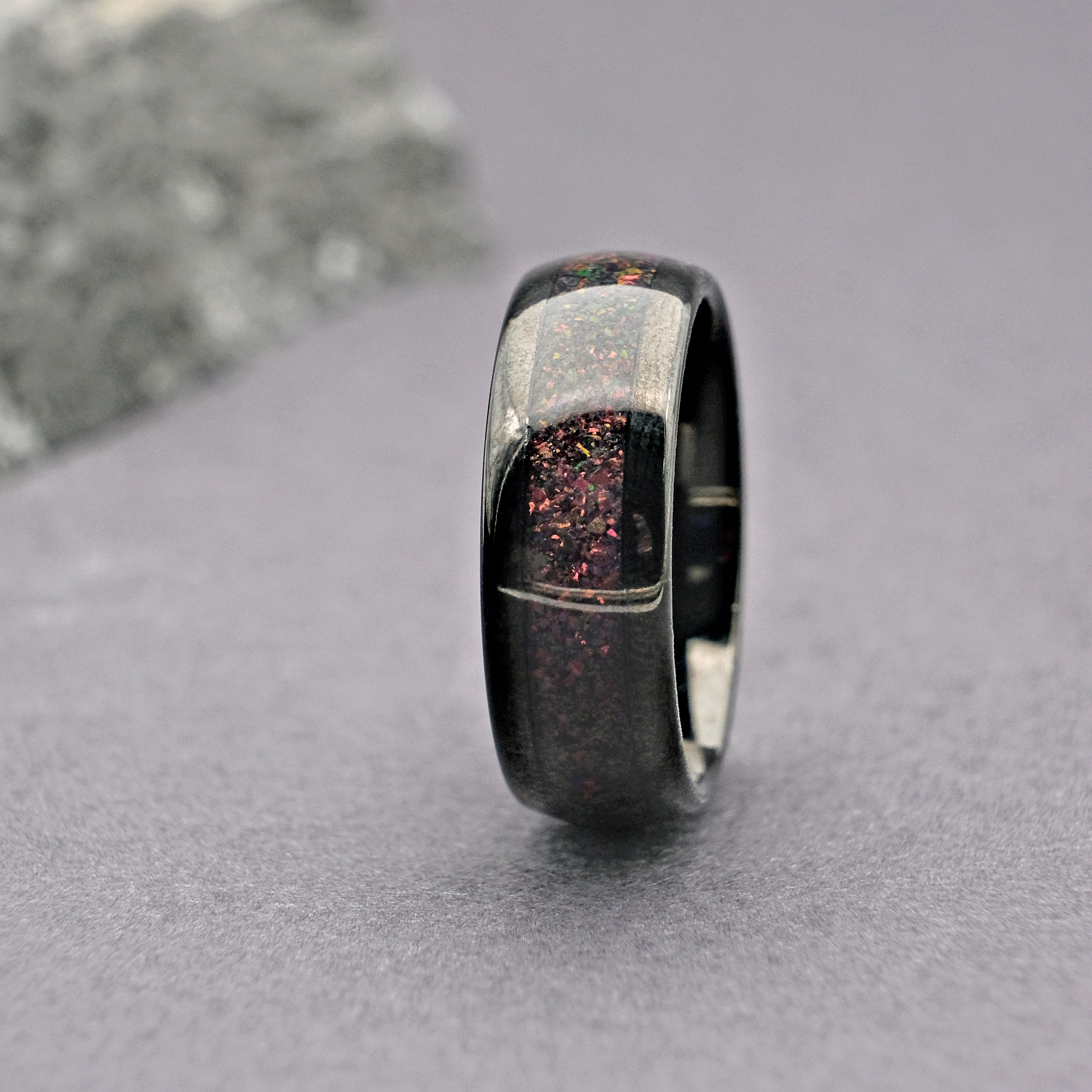 Sleek Black Tungsten Wedding Ring featuring a Black Fire Opal inlay, displayed vertically in a close-up shot.