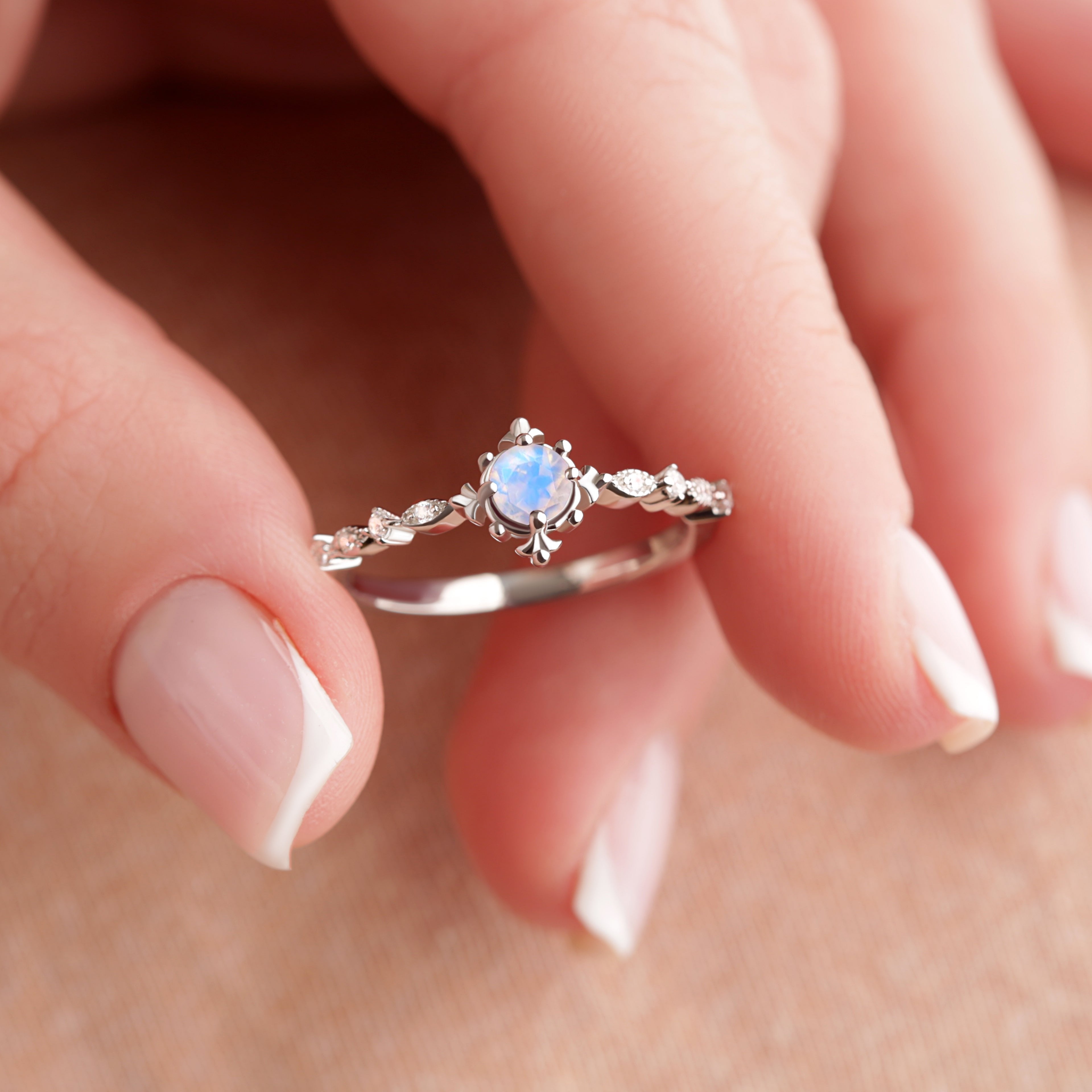 The MOON Vintage Sparkling Moonstone Engagement Ring in silver gold, held delicately by fingertips, highlighting the beautiful craftsmanship and Moonstone centerpiece.