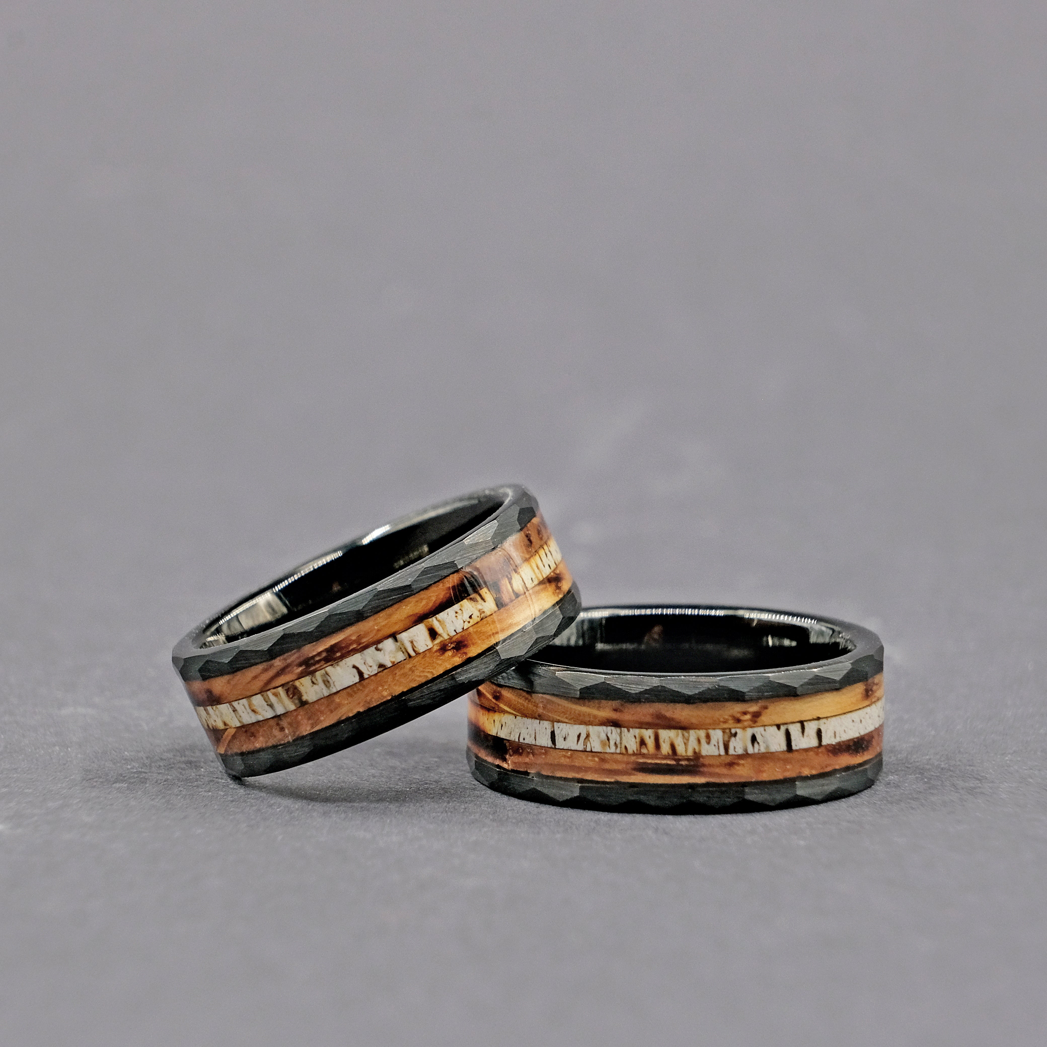 Set of Whiskey Barrel Wedding Rings displayed horizontally, featuring genuine whiskey barrel wood and polished tungsten carbide bands.